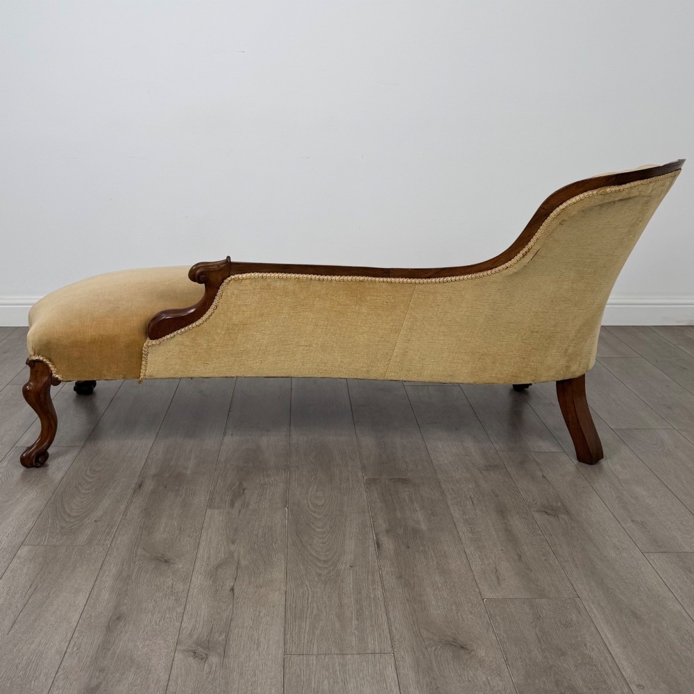 A Victorian mahogany chaise longue featuring ochre velvet button-backed upholstery, carved trim, and cabriole legs. View V