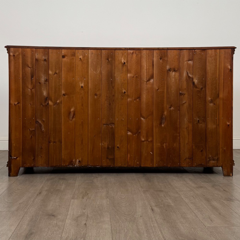 A twentieth-century warm oak sideboard featuring three upper drawers with brass handles above three cupboard doors decorated with geometric moulded panels and exterior brass H-hinges. View VI