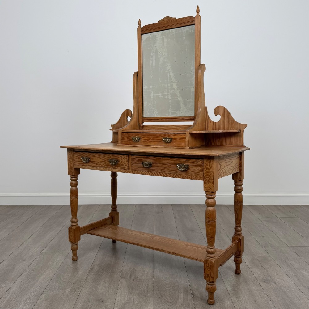 A Victorian pitch pine dressing table featuring a central swivel mirror, side scroll shelves, frieze drawers with brass handles, and turned legs with a low shelf. View II