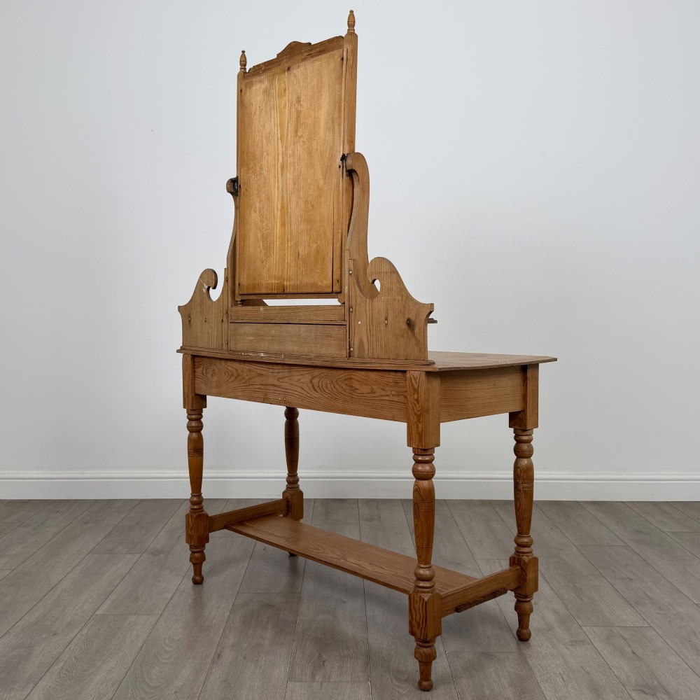 A Victorian pitch pine dressing table featuring a central swivel mirror, side scroll shelves, frieze drawers with brass handles, and turned legs with a low shelf. View VI