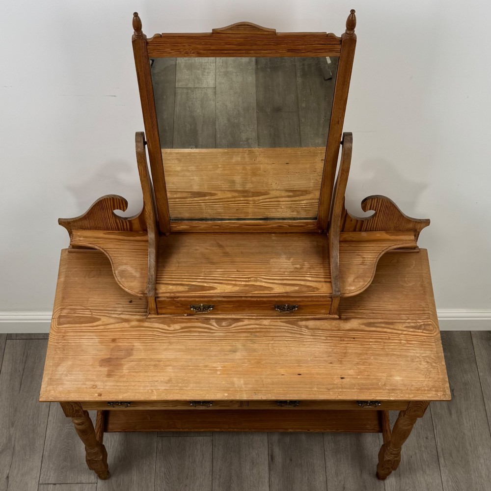 A Victorian pitch pine dressing table featuring a central swivel mirror, side scroll shelves, frieze drawers with brass handles, and turned legs with a low shelf. View IX