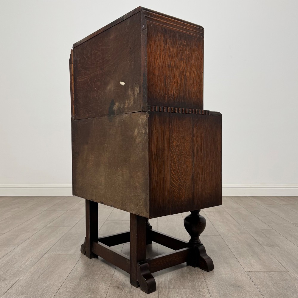 An early 20th-century dark oak writing bureau featuring a sloped fall-front lid above two drawers, supported on turned bulbous legs with stretchers. View VII