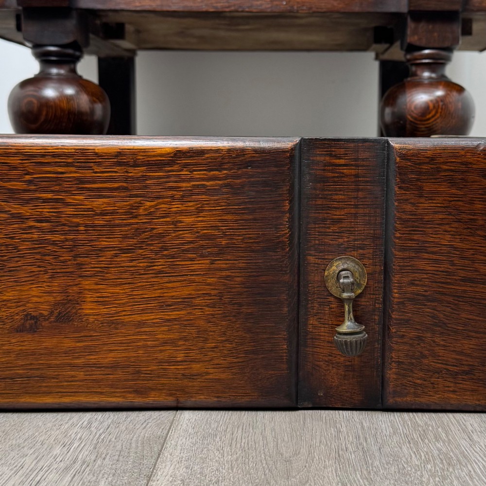 An early 20th-century dark oak writing bureau featuring a sloped fall-front lid above two drawers, supported on turned bulbous legs with stretchers. View XIII