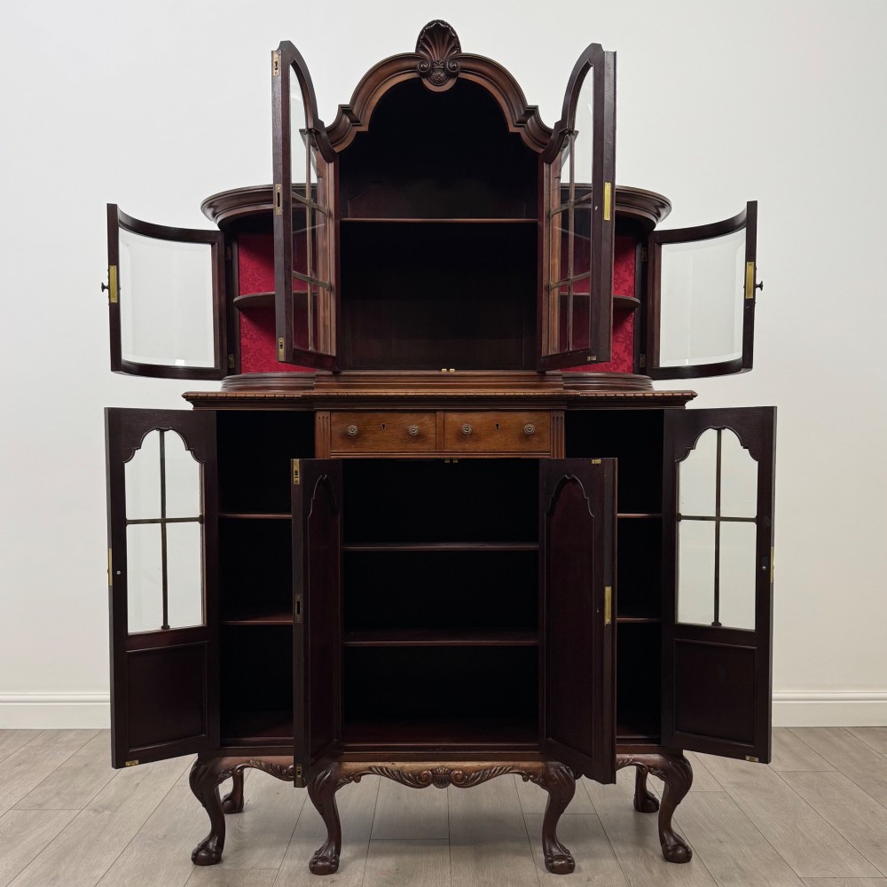 A 19th-century Queen Anne style dark walnut display cabinet featuring curved glass side sections, an arched central glazed door with a carved shell crest, and cabriole legs. View II