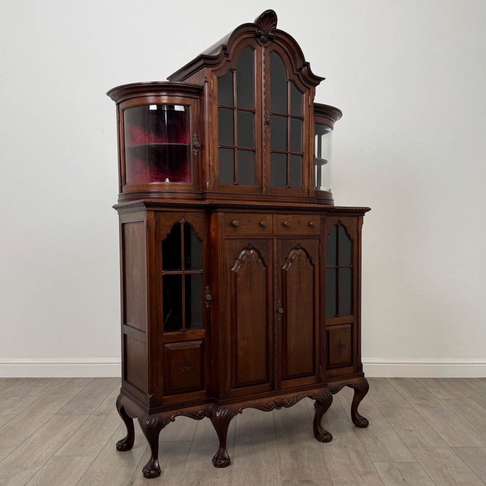 A 19th-century Queen Anne style dark walnut display cabinet featuring curved glass side sections, an arched central glazed door with a carved shell crest, and cabriole legs. View IX