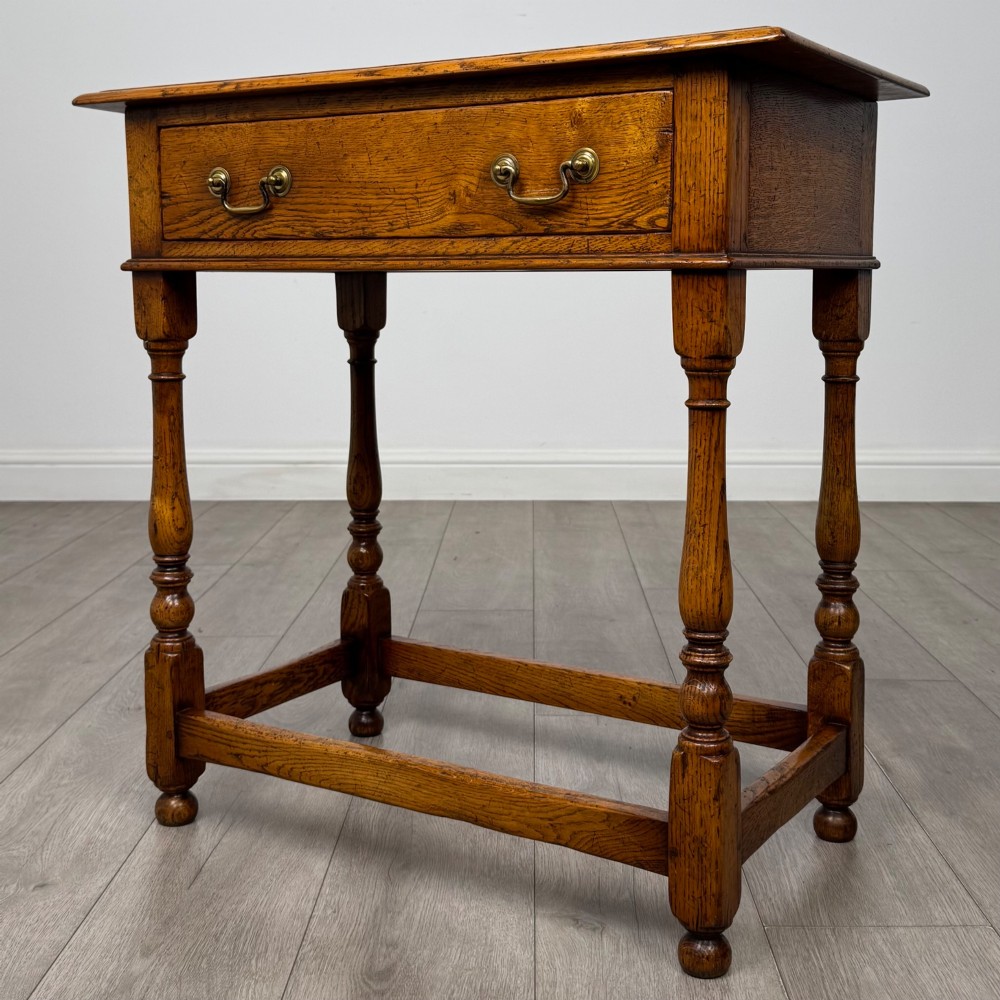 A golden oak side table featuring a single drawer with two brass handles, turned legs, and an lower stretcher base. View II