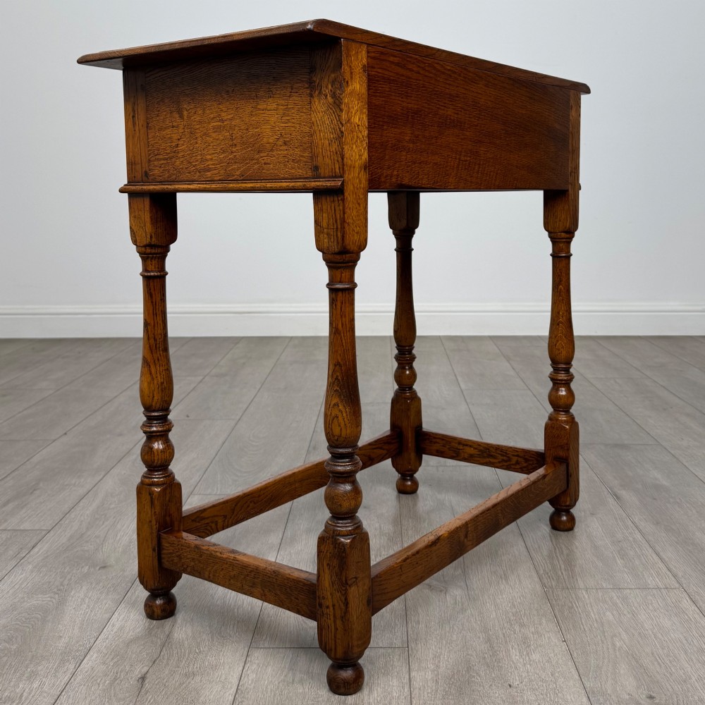 A golden oak side table featuring a single drawer with two brass handles, turned legs, and an lower stretcher base. View IV