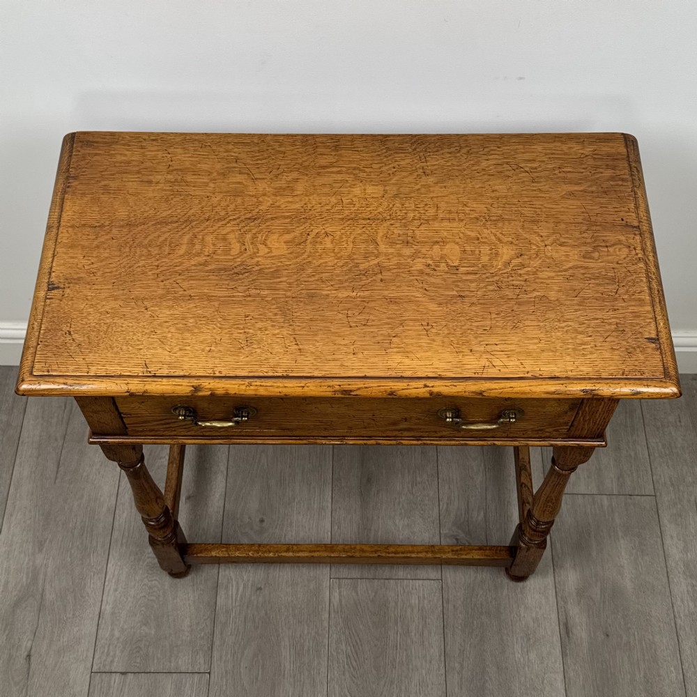 A golden oak side table featuring a single drawer with two brass handles, turned legs, and an lower stretcher base. View IX