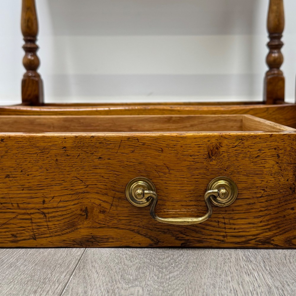 A golden oak side table featuring a single drawer with two brass handles, turned legs, and an lower stretcher base. View XI