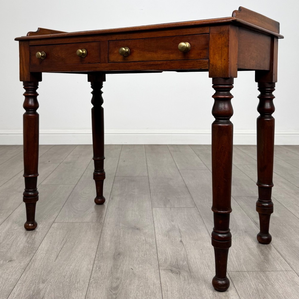 A Victorian mahogany writing table featuring two frieze drawers with brass knob handles, turned legs, and a low gallery back. View II