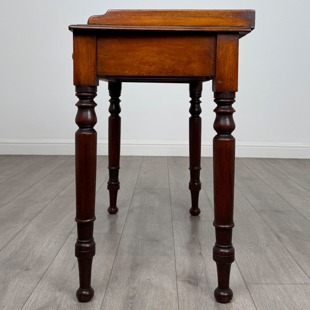 A Victorian mahogany writing table featuring two frieze drawers with brass knob handles, turned legs, and a low gallery back. View III