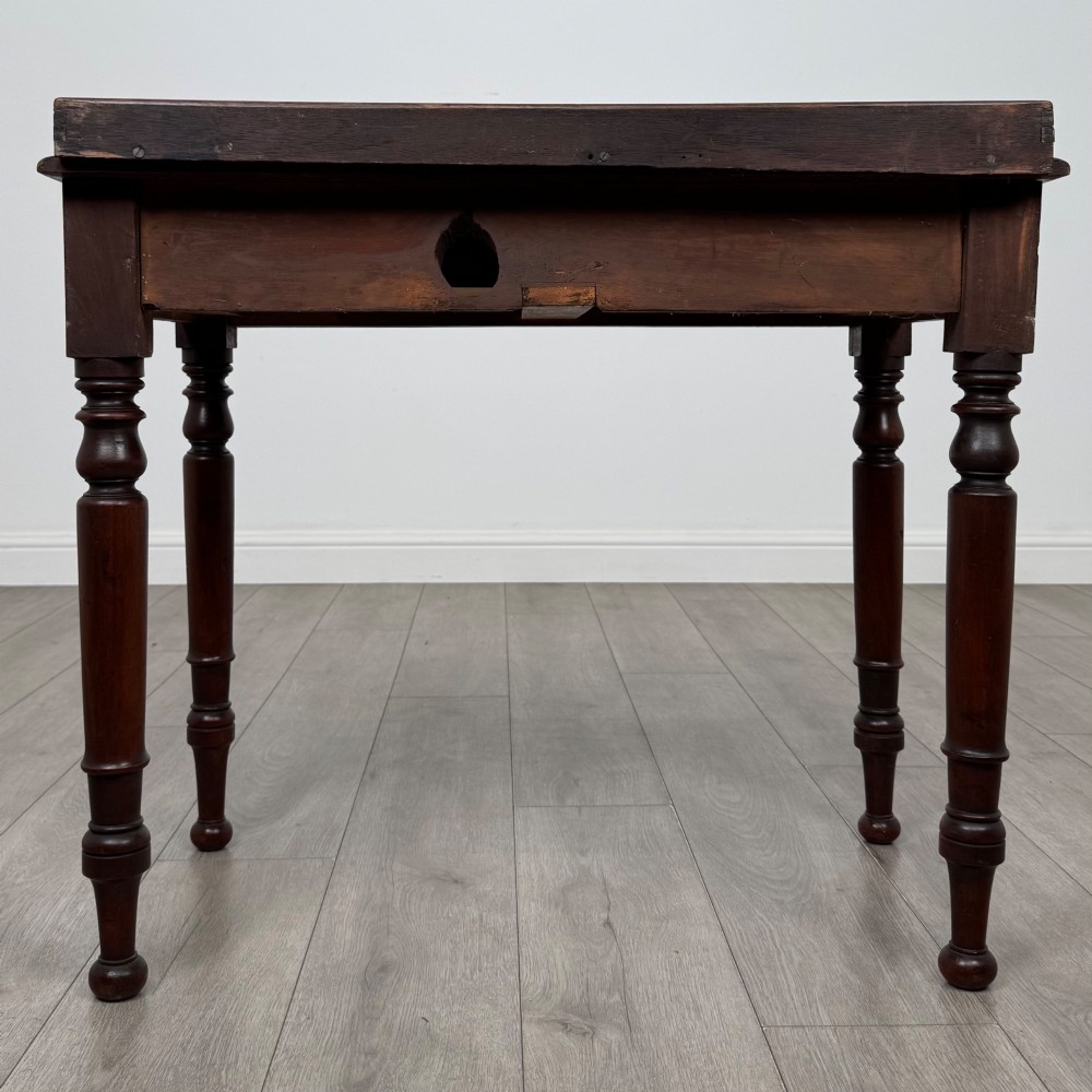 A Victorian mahogany writing table featuring two frieze drawers with brass knob handles, turned legs, and a low gallery back. View V