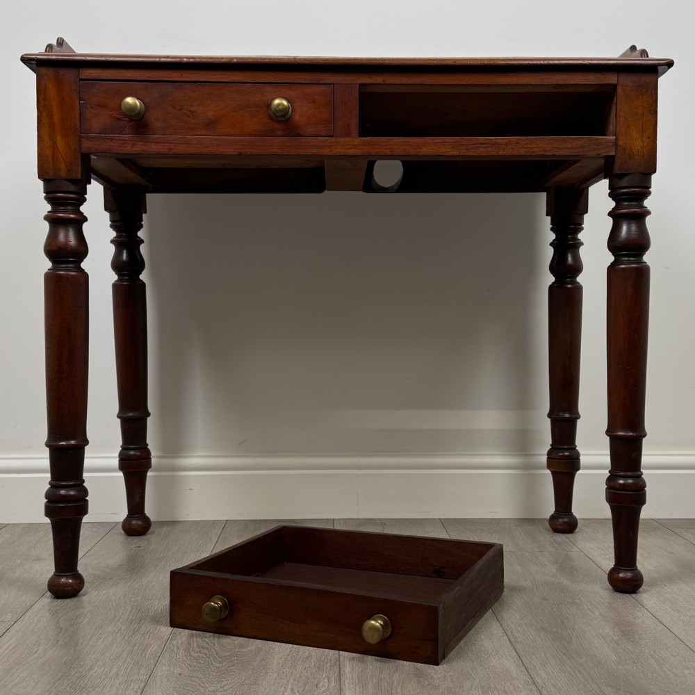 A Victorian mahogany writing table featuring two frieze drawers with brass knob handles, turned legs, and a low gallery back. View X