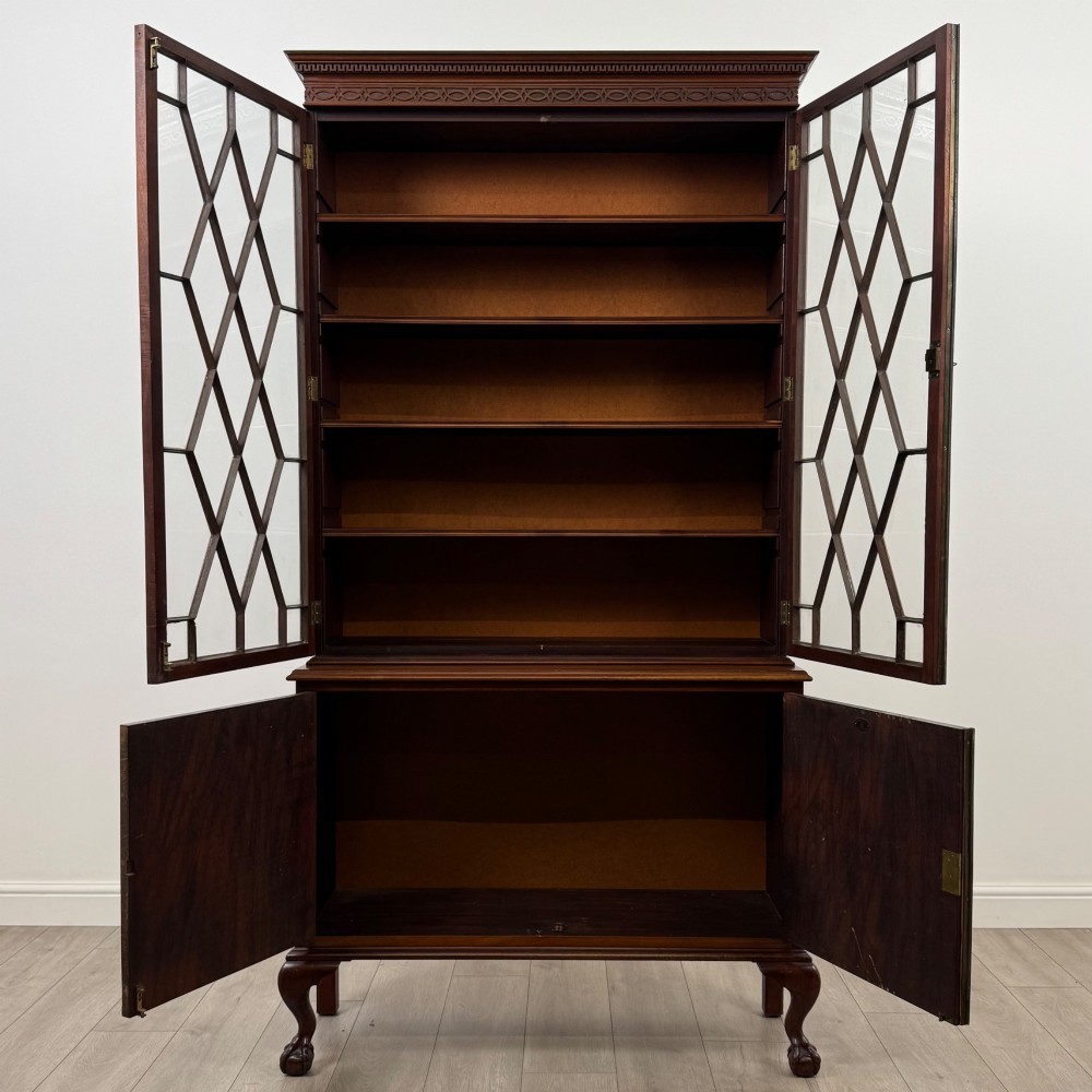 A 20th-century Chippendale style mahogany bookcase featuring two upper glazed doors with diamond pattern astragal glazing and a two-door cupboard base raised on cabriole legs with claw and ball feet. View II