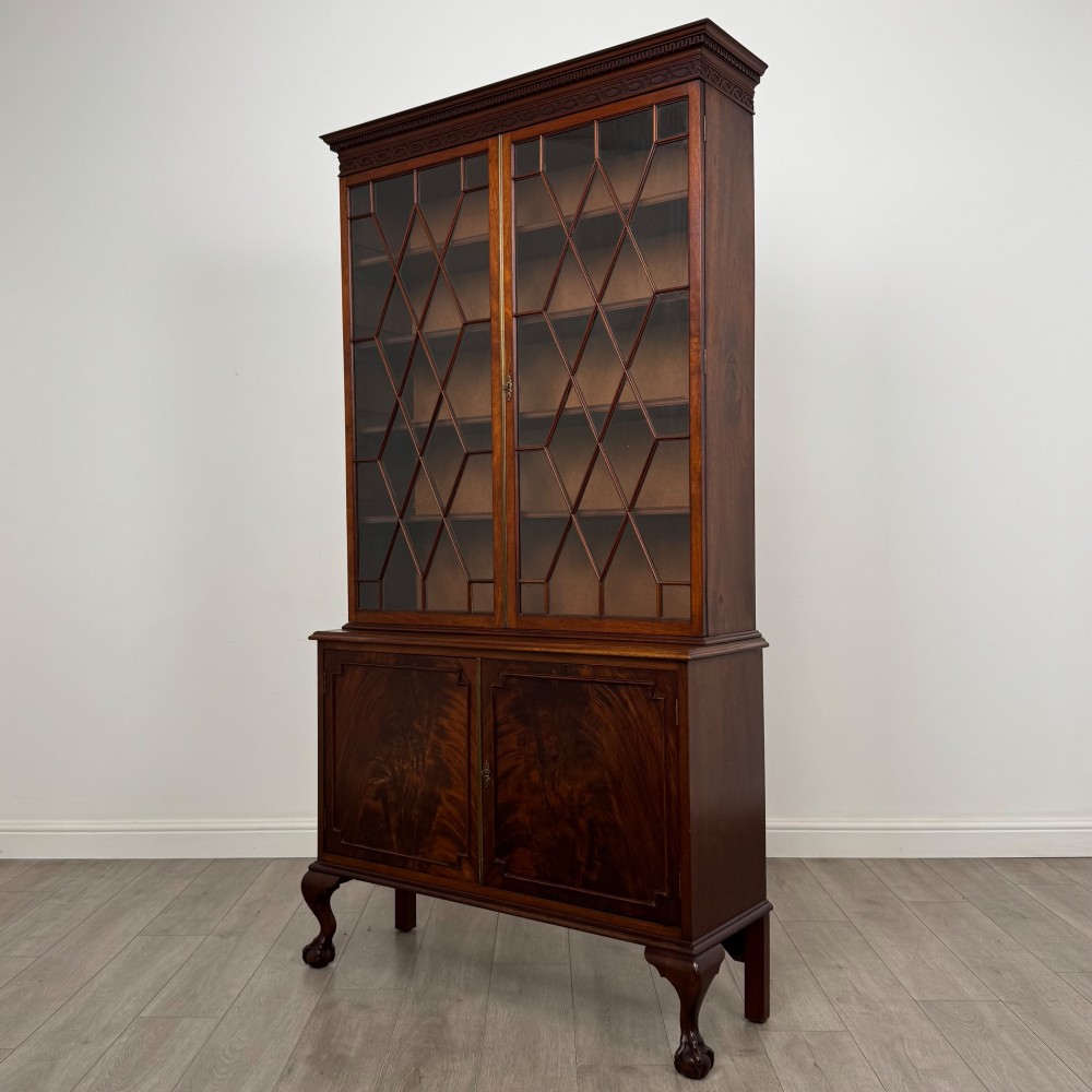A 20th-century Chippendale style mahogany bookcase featuring two upper glazed doors with diamond pattern astragal glazing and a two-door cupboard base raised on cabriole legs with claw and ball feet. View III