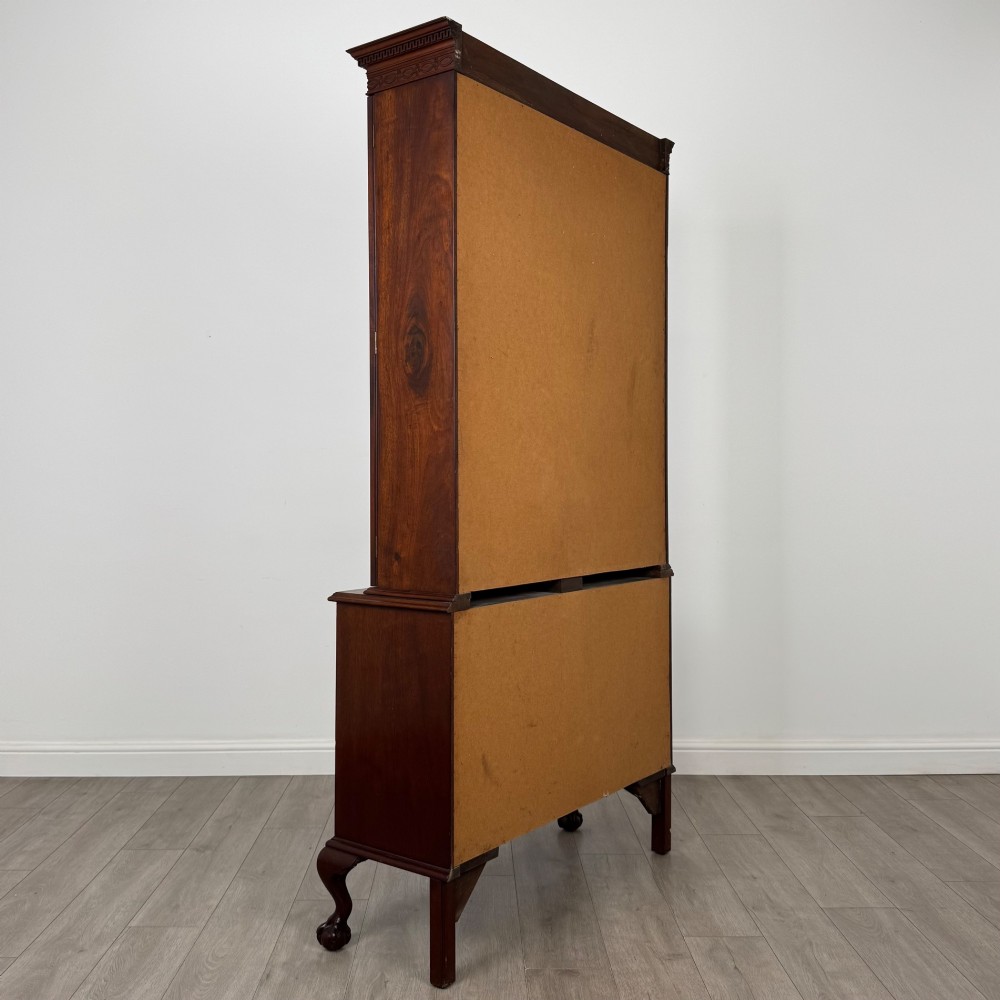 A 20th-century Chippendale style mahogany bookcase featuring two upper glazed doors with diamond pattern astragal glazing and a two-door cupboard base raised on cabriole legs with claw and ball feet. View V