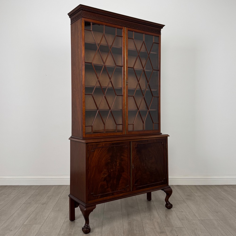 A 20th-century Chippendale style mahogany bookcase featuring two upper glazed doors with diamond pattern astragal glazing and a two-door cupboard base raised on cabriole legs with claw and ball feet. View IX