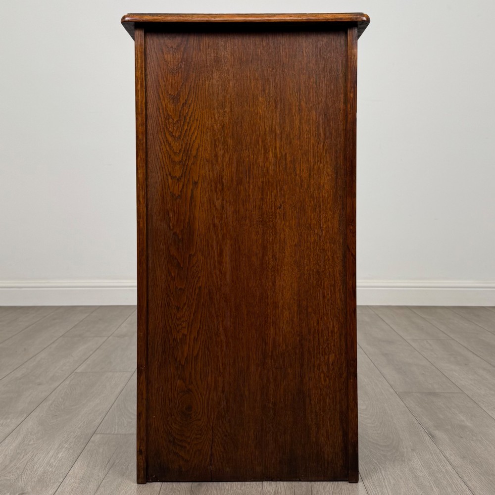 An antique dark oak tambour cabinet featuring a vertical wooden slat roll-front door and top brass locking mechanism. View VI