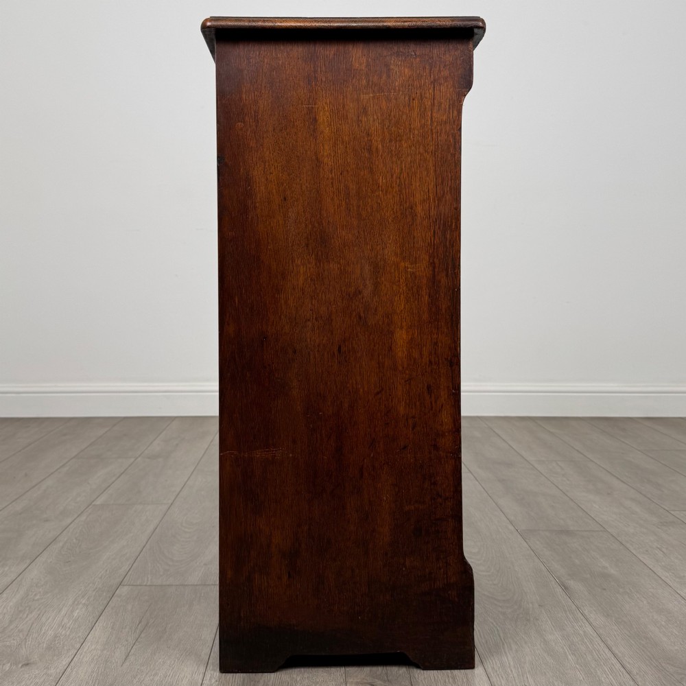 An antique dark oak tambour cabinet featuring a vertical wooden slat roll-front door and top brass locking mechanism. View VIII