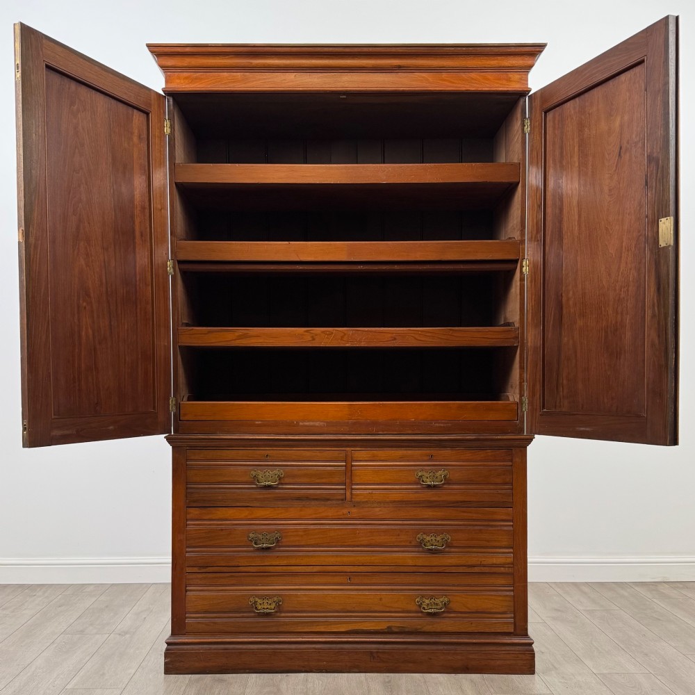An Edwardian walnut linen press featuring a moulded top cornice, two large upper recessed panel doors, and a lower chest of drawers with brass drop handles. View II