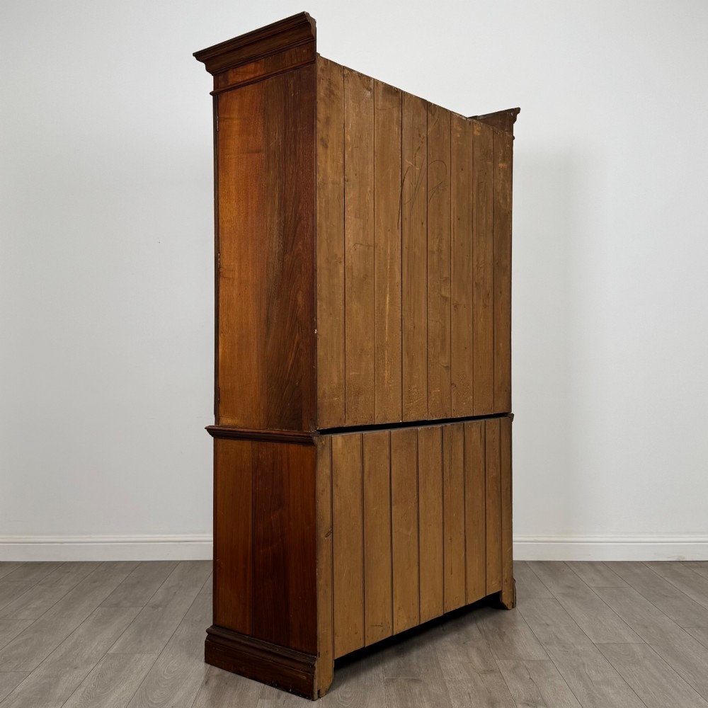 An Edwardian walnut linen press featuring a moulded top cornice, two large upper recessed panel doors, and a lower chest of drawers with brass drop handles. View V
