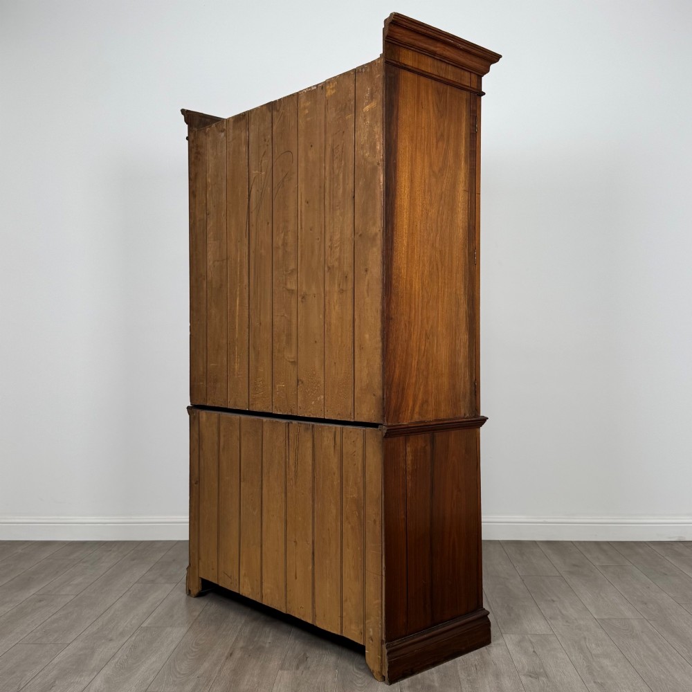 An Edwardian walnut linen press featuring a moulded top cornice, two large upper recessed panel doors, and a lower chest of drawers with brass drop handles. View VII