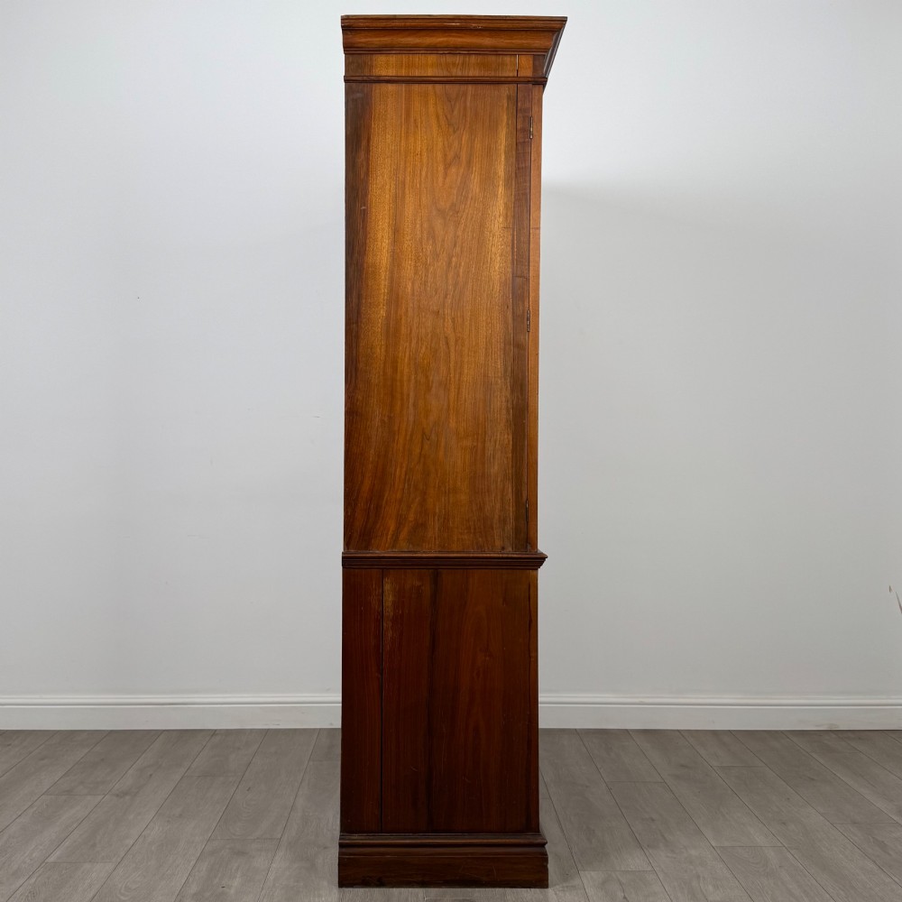 An Edwardian walnut linen press featuring a moulded top cornice, two large upper recessed panel doors, and a lower chest of drawers with brass drop handles. View VIII
