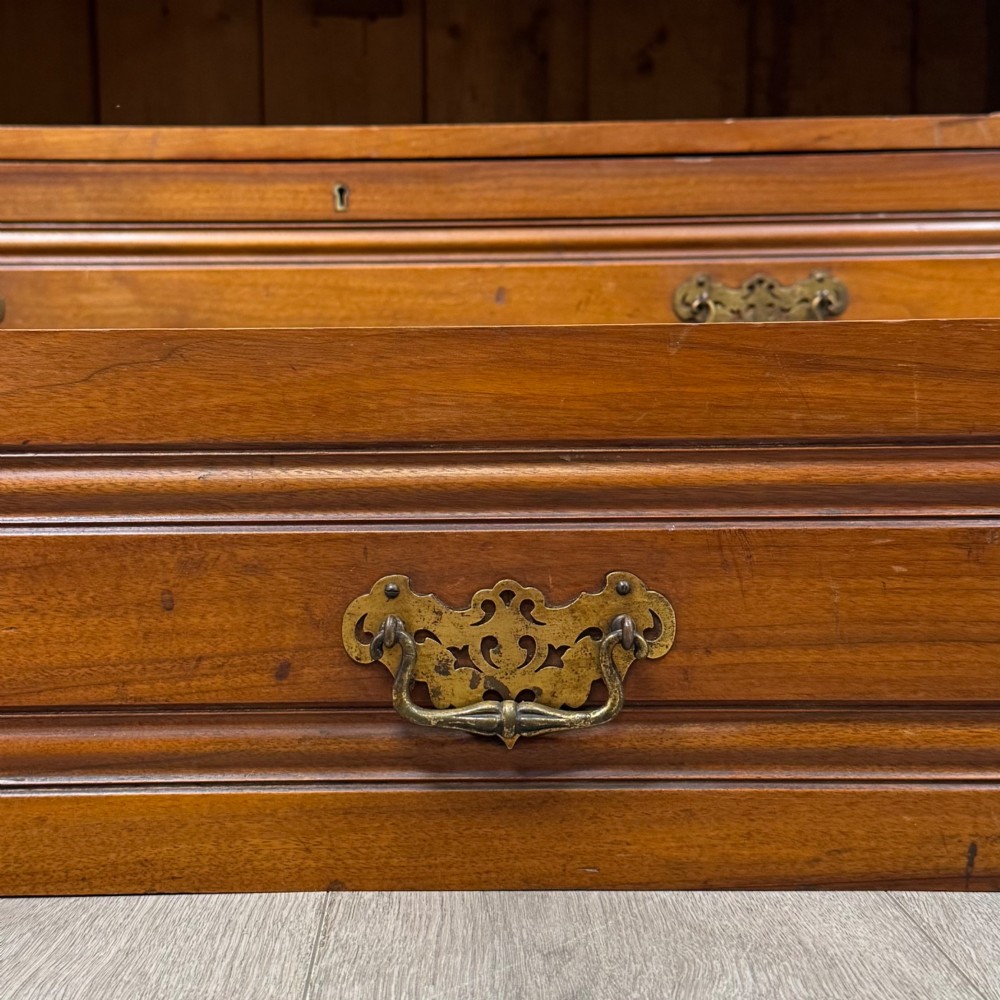 An Edwardian walnut linen press featuring a moulded top cornice, two large upper recessed panel doors, and a lower chest of drawers with brass drop handles. View XI