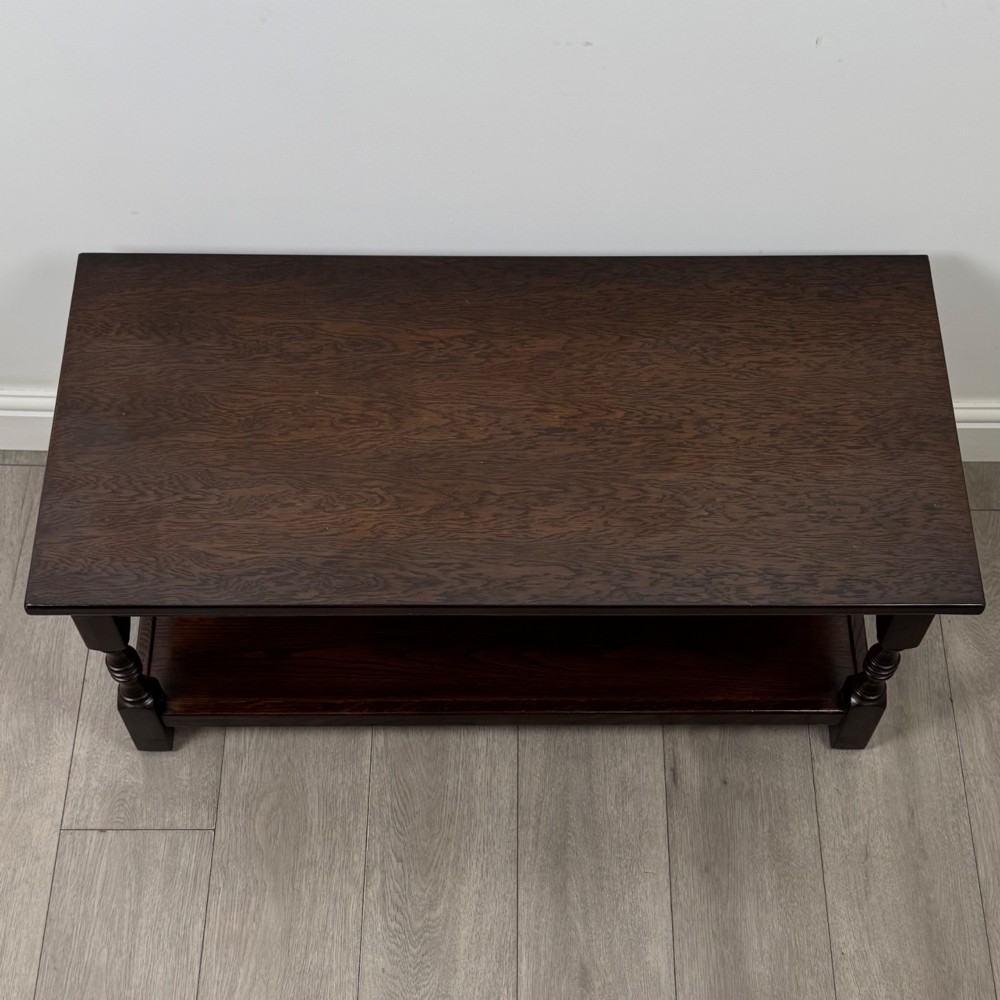 A dark carved oak coffee table featuring an arcaded carved apron, turned legs, and an integrated lower shelf. View VIII
