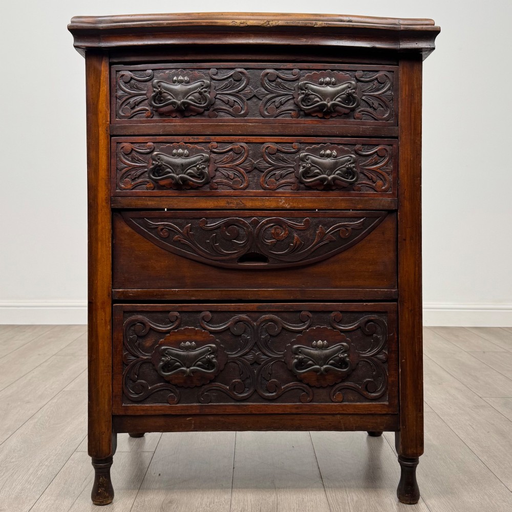 A 19th-century Victorian walnut chest of drawers featuring ornate relief carvings across the drawer fronts and metal drop handles.
