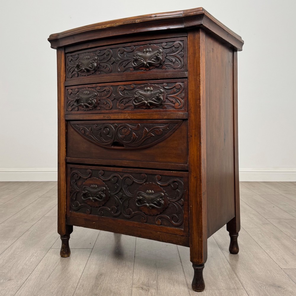 A 19th-century Victorian walnut chest of drawers featuring ornate relief carvings across the drawer fronts and metal drop handles. View II