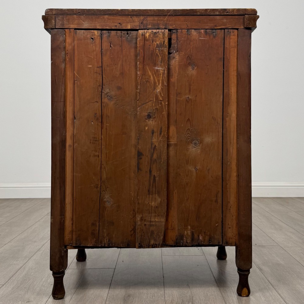 A 19th-century Victorian walnut chest of drawers featuring ornate relief carvings across the drawer fronts and metal drop handles. View V
