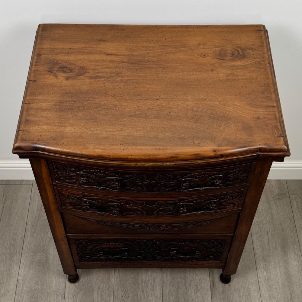A 19th-century Victorian walnut chest of drawers featuring ornate relief carvings across the drawer fronts and metal drop handles. View IX
