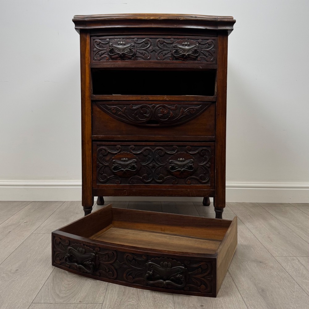 A 19th-century Victorian walnut chest of drawers featuring ornate relief carvings across the drawer fronts and metal drop handles. View X