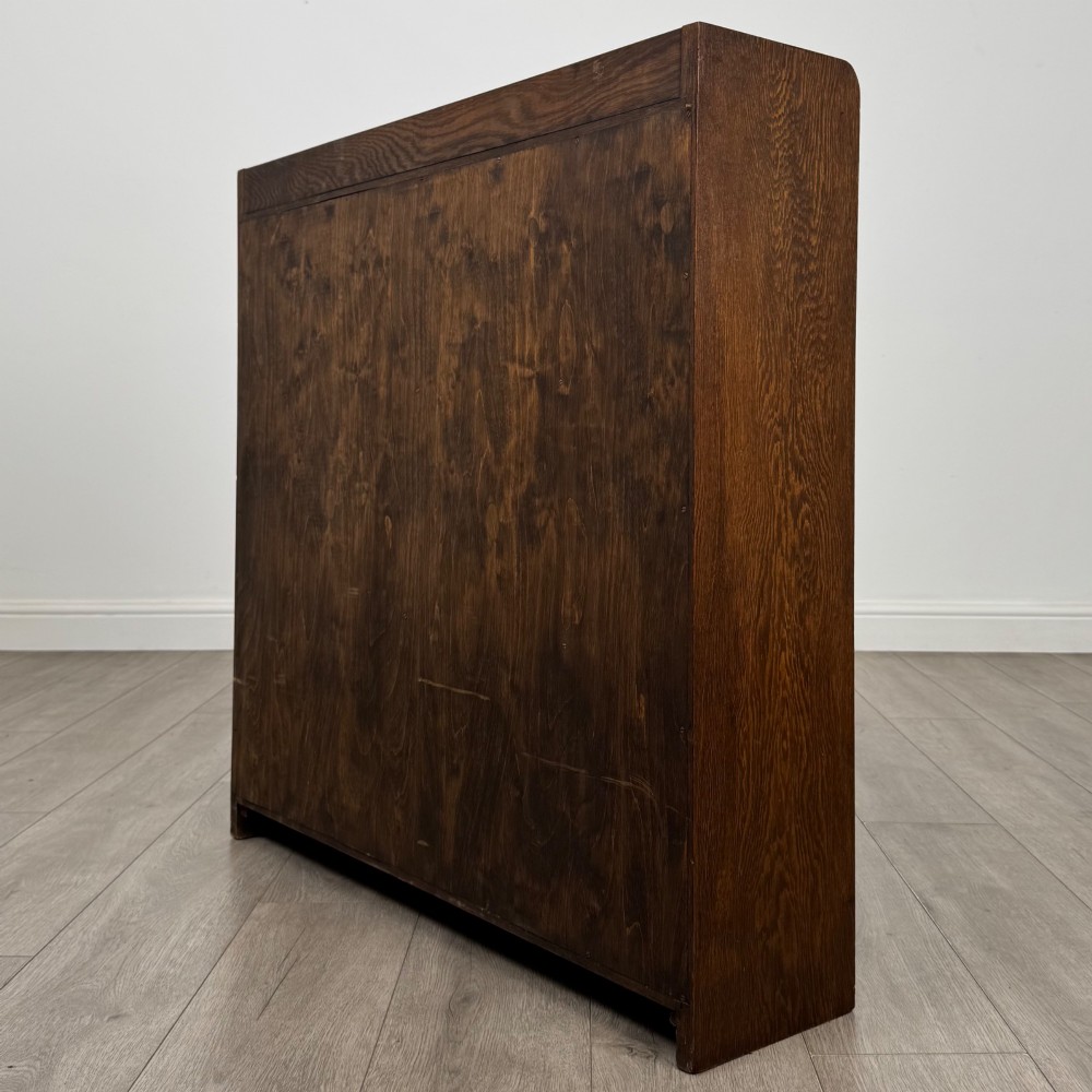 A mid-twentieth-century dark oak display cabinet featuring three interior shelf tiers enclosed by sliding glass doors. View VII