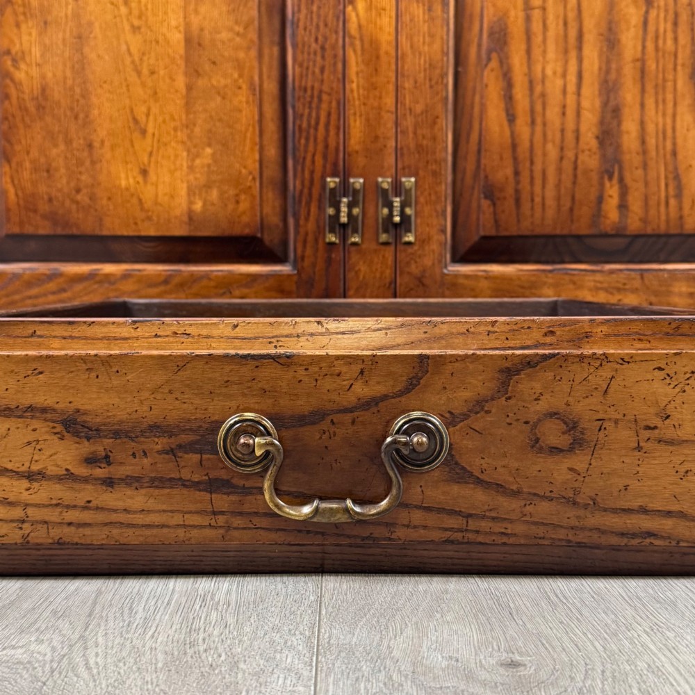 A large medium brown oak sideboard featuring four upper drawers with brass handles above four cupboard doors with arched wood panels. View XII