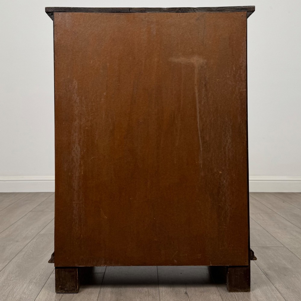 A small dark oak cupboard featuring a single carved top drawer above a panelled cupboard door with iron hinges. View VI
