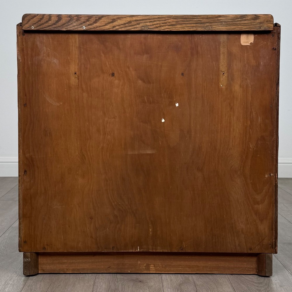 An antique golden oak chest of four drawers fitted with decorative brass drop handles on a plinth base. View V