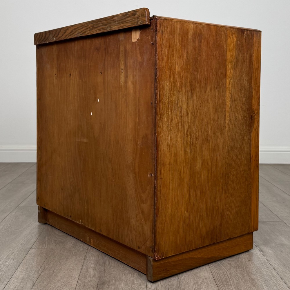 An antique golden oak chest of four drawers fitted with decorative brass drop handles on a plinth base. View VI