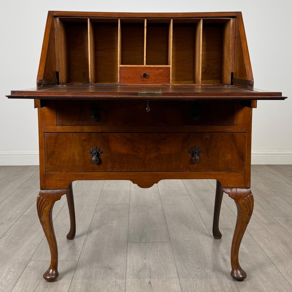 An antique Edwardian burr walnut slant-front bureau featuring two drawers with metal handles, supported by carved cabriole legs. View II