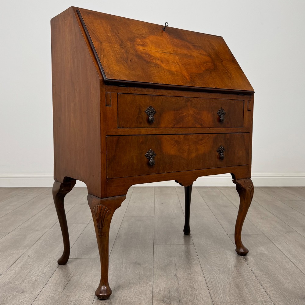 An antique Edwardian burr walnut slant-front bureau featuring two drawers with metal handles, supported by carved cabriole legs. View IX