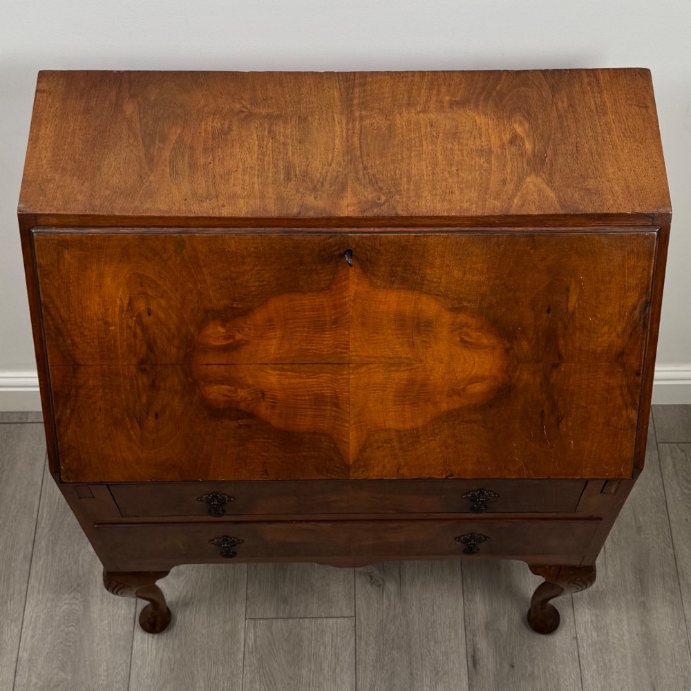 An antique Edwardian burr walnut slant-front bureau featuring two drawers with metal handles, supported by carved cabriole legs. View X