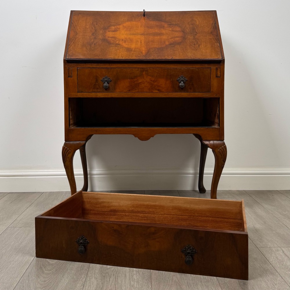An antique Edwardian burr walnut slant-front bureau featuring two drawers with metal handles, supported by carved cabriole legs. View XII