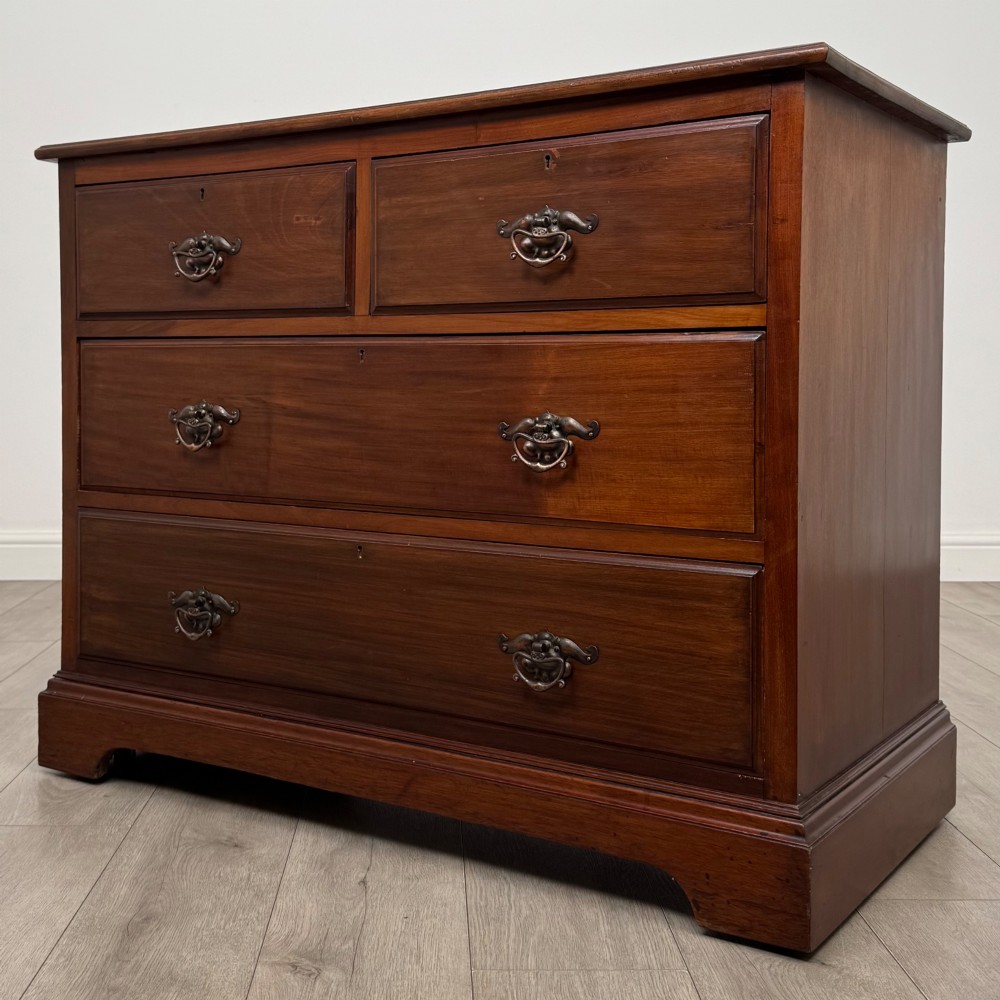 An antique mahogany chest of drawers featuring two short top drawers over two long lower drawers with decorative metal handles on a plinth base. View II