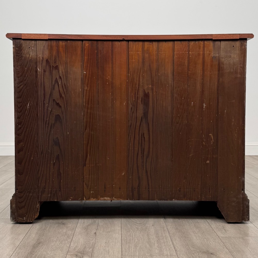 An antique mahogany chest of drawers featuring two short top drawers over two long lower drawers with decorative metal handles on a plinth base. View V