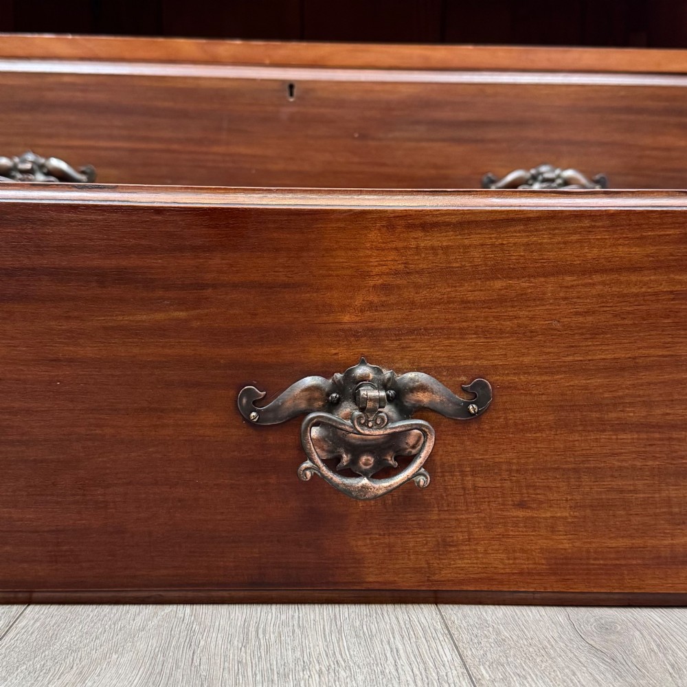 An antique mahogany chest of drawers featuring two short top drawers over two long lower drawers with decorative metal handles on a plinth base. View XI