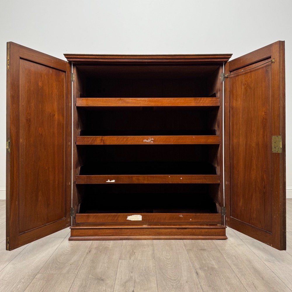 An antique early twentieth-century two-door walnut linen cupboard featuring double panelled doors, a moulded top cornice, and a central brass teardrop handle. View II