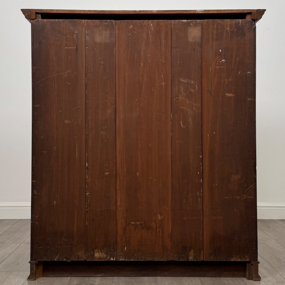 An antique early twentieth-century two-door walnut linen cupboard featuring double panelled doors, a moulded top cornice, and a central brass teardrop handle. View VI