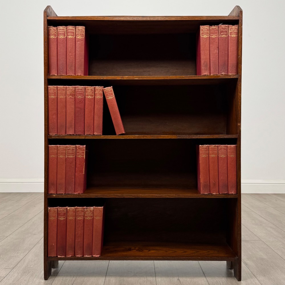 An Edwardian dark oak open bookcase featuring four fixed shelves and shaped side panels.