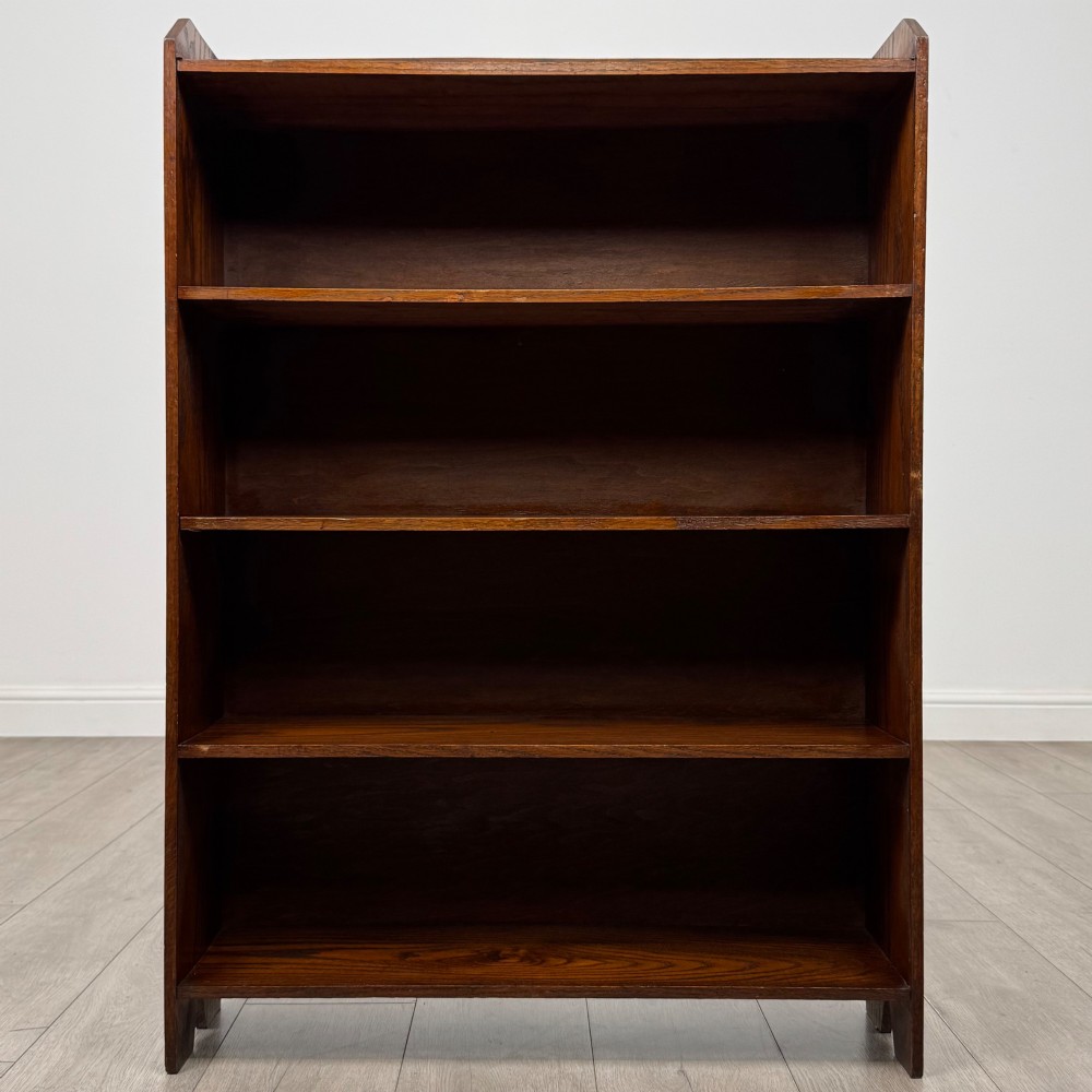 An Edwardian dark oak open bookcase featuring four fixed shelves and shaped side panels. View II